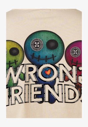 Camiseta gráfica colorida que presenta tres calaveras de dibujos animados con acentos de costura, etiquetadas como "AMIGOS INCORRECTOS" en letras grandes, sobre un fondo claro.