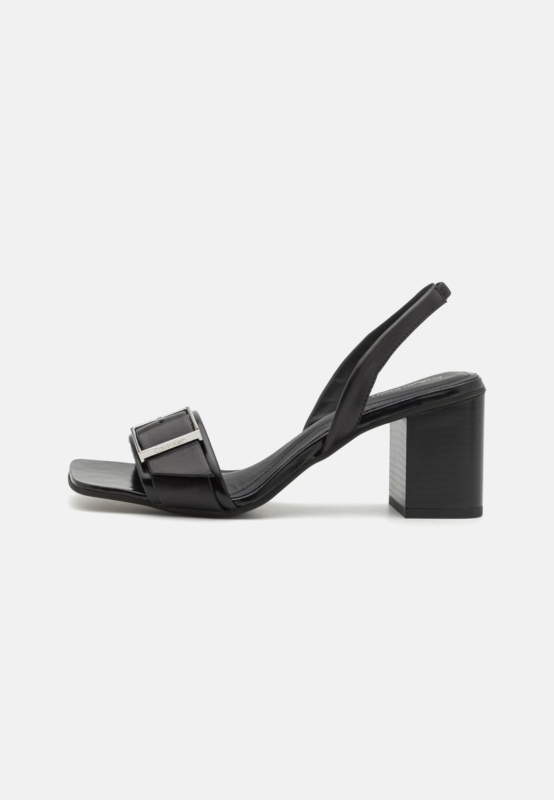Black slingback heels with a square toe, block heel, and metallic buckle detail. Made of smooth synthetic material.