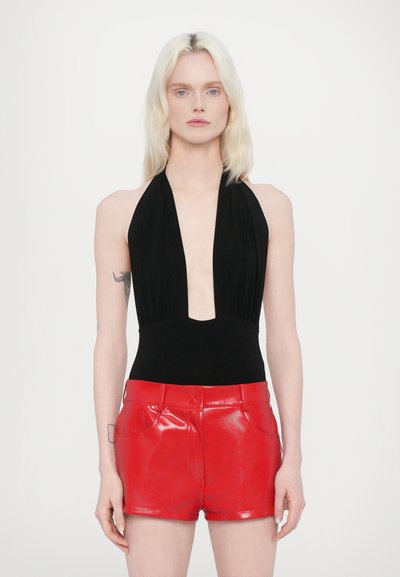 Zwarte halterhals bodysuit met diepe V-hals, gecombineerd met glanzende rode leren shorts met voorzakken en een aansluitende snit.