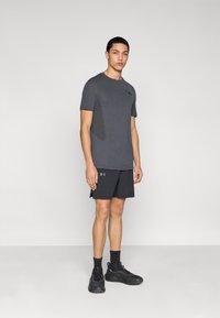 Αθλητική εμφάνιση με σκουρόχρωμο γκρι κοντομάνικο πουκάμισο από υφή υφάσματος και μαύρο σορτς. Περιλαμβάνει μαύρα αθλητικά παπούτσια και κάλτσες.