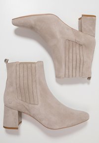 Botines de ante beige con punta afilada, tacón cuadrado y paneles laterales elásticos con costuras verticales. Textura suave con un sutil logotipo.
