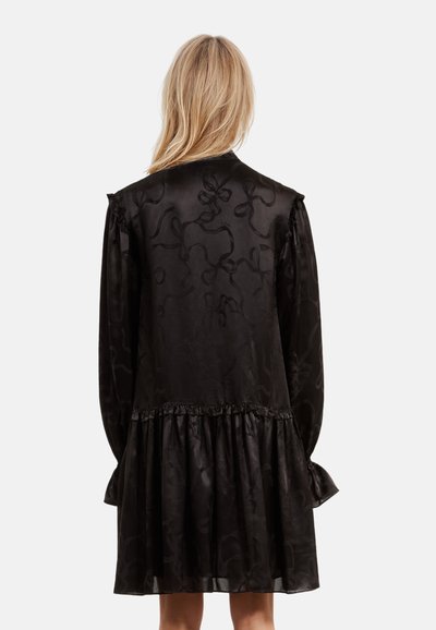Schwarzes Kleid aus glattem Stoff mit einem dezenten Blumenmuster, das eine geraffte Taille und lange Ärmel mit Rüschenakzenten aufweist.