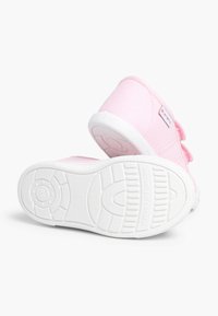 Rosa Leinenschuhe mit weißen Gummisohlen, die mit einem Klettverschlussriemen ausgestattet sind. Die Unterseite zeigt ein strukturiertes Profilmuster für guten Halt.