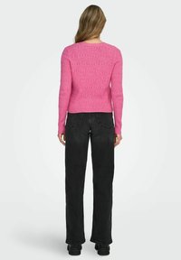 Maglione rosa a coste con scollo rotondo e maniche lunghe, abbinato a pantaloni neri a vita alta e gamba larga. Tessuto liscio, design casual.