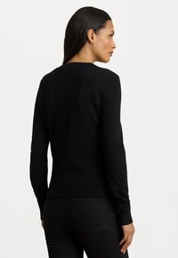 Μαύρο πουλόβερ με μακριά μανίκια και στρογγυλή λαιμόκοψη, με εφαρμοστή σχεδίαση και ραβδωτές λεπτομέρειες στα μανίκια και το στρίφωμα.