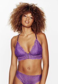 Bralette in pizzo viola e mutandine abbinate con bordi scampanati, intricati motivi floreali e dettaglio di chiusura frontale.