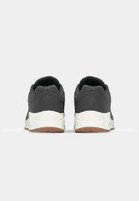 Czarne buty sportowe o gładkim wykończeniu, biała podeszwa środkowa i gumowa podeszwa zewnętrzna. Wyś cushioning w kołnierzu oraz zaokrąglony obcas dla wsparcia.