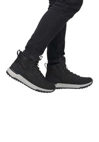 Czarne półwysokie buty trekkingowe z szarym spodem, z teksturowaną cholewką, z zapięciem na sznurowadła oraz bocznym zamkiem. Trwała i uniwersalna konstrukcja.