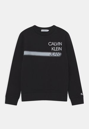 Sweat-shirt noir à manches longues avec le texte "CALVIN KLEIN JEANS" en haut à gauche et une bande horizontale gris clair traversant la poitrine.
