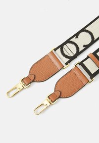 Sangle en tissu tissé avec un fond crème et un motif de logo noir, extrémités en cuir marron et fermoirs en métal doré pour l'attache.