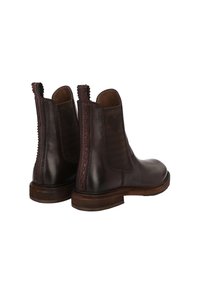 Bottes en cuir marron à hauteur de cheville avec des panneaux latéraux élastiques et des détails de surpiqûres rouges à l'arrière, disposant d'un bout rond et d'une semelle en caoutchouc.