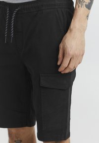 Zwarte cargoshorts van katoen, met een elastische tailleband, trekkoord, zijzak en een gladde, matte textuur.