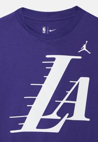 Μωβ μπλουζάκι από βαμβάκι με μεγάλο λευκό γράμμα "LA" και λογότυπο Jumpman στη λαιμόκοψη, με απαλό ύφασμα.