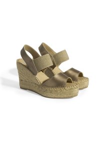 Les sandales à talons en bronze présentent une semelle en jute tissée, un design à bout ouvert et des bandes élastiques pour un maintien sécurisé. Texture lisse et couleur neutre.