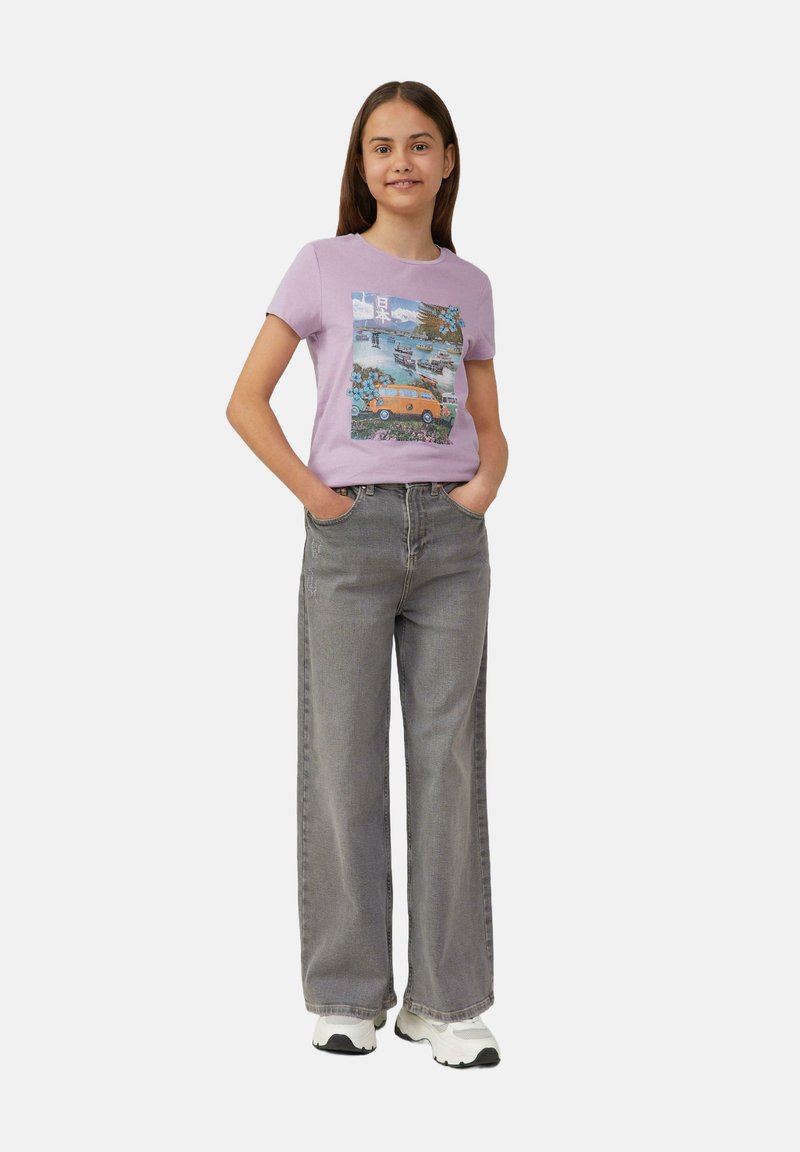 Lila T-Shirt mit einem bunten Grafikdesign, kombiniert mit locker sitzenden grauen Jeans und weißen Sneakers. Einfaches, lässiges Outfit.