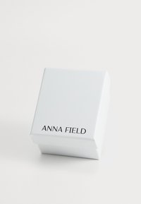 White square gift box with a smooth surface, featuring "ANNA FIELD" printed in black bold font on the front. Closed, no visible contents.