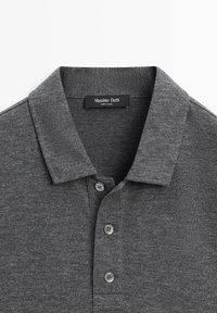 Grå poloshirt med tekstureret stof, tre-knaps stolpelukning og klassisk krave. Labelen viser "Massimo Dutti," fremstillet i Kina.