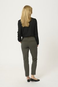 Černá blůza s dlouhým rukávem v kombinaci s olivově zelenými slim-fit kalhotami a černými balerínami, zobrazeno zezadu na jednolitém pozadí.