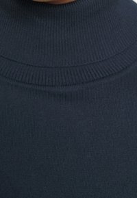 Pull à col roulé bleu marine à texture côtelée, avec un col haut et un détail côtelé horizontal au niveau de l'encolure.