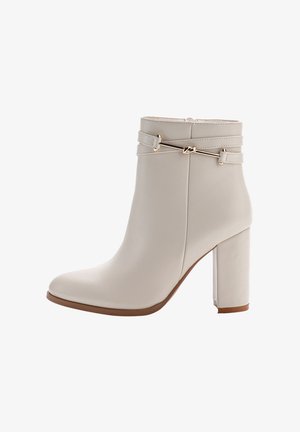Beige Knöchelstiefel mit glatter Lederoberfläche, Blockabsatz und doppelt geschnittenem Akzent mit goldenen Beschlägen. Rund zulaufende Zehenform.