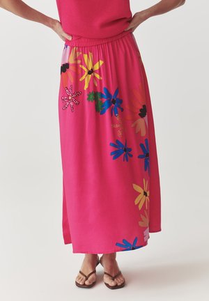 Jupe maxi rose avec une taille froncée, ornée de motifs floraux vibrants en bleu, jaune, rose et vert. Fabriquée dans un tissu doux et léger.