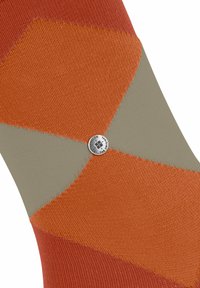 Chaussettes rayées présentant des motifs géométriques orange et gris avec une surface texturée et un détail de bouton argenté au centre.