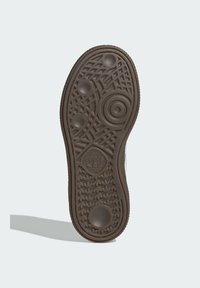 Hnědá gumová podrážka s texturovanými vzory, včetně oblíbených kruhových a liniových designů, a s vyraženým logem ve spodní části uprostřed.