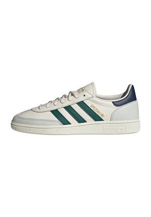 Weißer Adidas Spezial Sneaker mit grünen Streifen, navyblauem Fersenlaschen und strukturiertem Profil, seitlich auf weißem Hintergrund dargestellt.