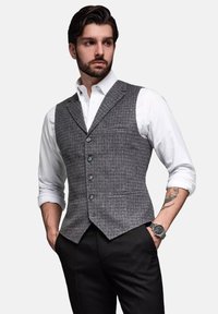 Grijs geruit vest met vijf knopen, getailleerde pasvorm, gecombineerd met een wit overhemden en zwarte broek. Glad stof met een lichte textuur.