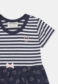 Pasiasta sukienka w granatowo-białe poziome paski, okrągły dekolt, haft w kształcie serca, a także falbaniasty dół z różowymi wzorami serc.