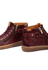 Zapatillas de alta con cordones burdeos de cuero, con cremallera lateral, puntera redonda, detalles en color beige y suela de goma texturizada.