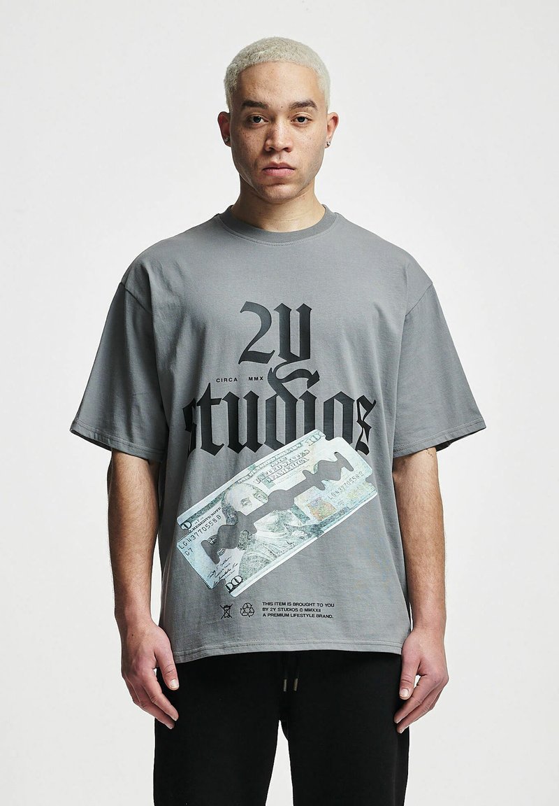 Camiseta gris de gran tamaño con texto gráfico negro y diseño impreso de un billete de 100 dólares. Mangas cortas y cuello redondo, fabricada en algodón.