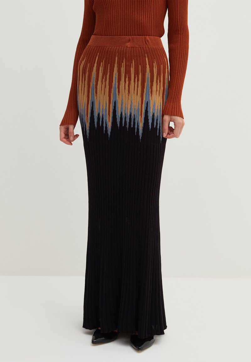 Rippstrick-Maxi-Rock mit einem Farbverlaufsmuster in Orange, Beige und Blau oben, der sich nach unten hin in Schwarz verwandelt.