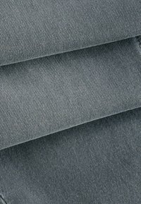 Ciemnoszara tkanina dżinsowa w złożeniach, ukazująca gładką fakturę i subtelny diagonalny wzór splotu. Powierzchnia jest jednolita, bez widocznych zdobień.