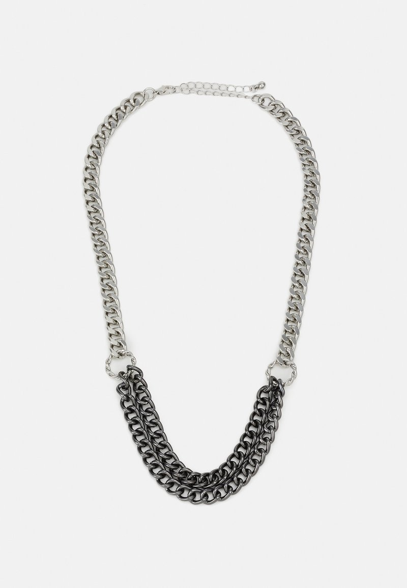 Collier en chaîne métallique avec des maillons argentés et noirs alternés. Présente un design à trois niveaux et un fermoir avec une chaîne ajustable.