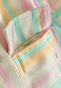 Närbild av en tygficka med pastellfärgade vertikala ränder i rosa, gult, grönt, blått och beige på ett texturerat textilmaterial.