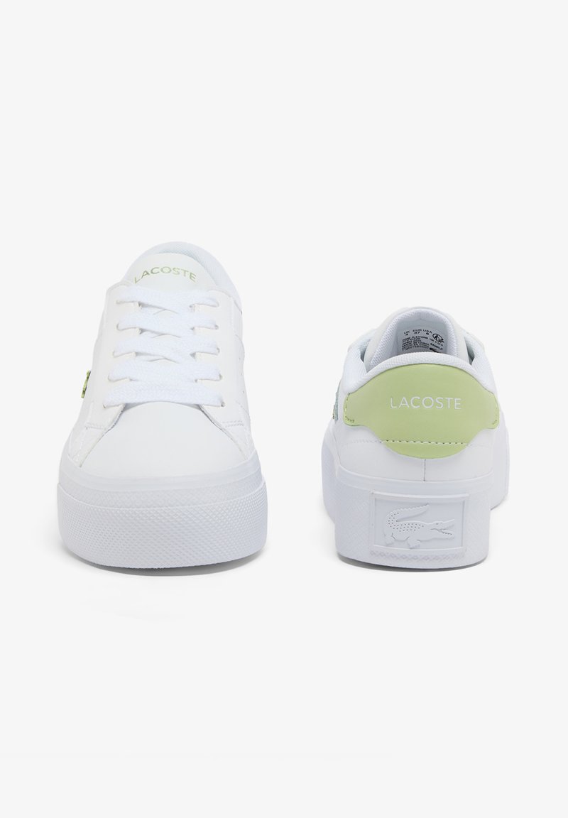 White Lacoste sneakers with green heel accents, one showing front laces, the other showing back with crocodile logo on sole.