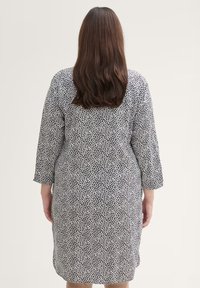Schwarz-weiß gemustertes Kleid mit Dreiviertelärmel, knielanger Design und lockerer Passform. Glatte Textur, keine sichtbaren Beschläge.