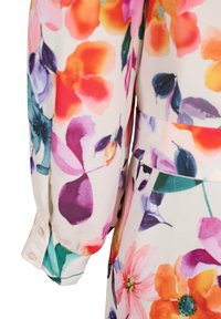Vêtement à manches longues avec imprimé floral multicolore en nuances d’orange, violet, rose et vert sur fond clair.
