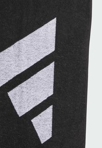 Czarny ręcznik o fakturowanej powierzchni z dużym białym geometrycznym wzorem trzech splatających się kształtów.