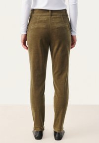 Olijfgroene ribfluwelen broek met een slim fit, voorzien van achterzakken, taps toelopende benen en een subtiele textuur. G gedragen met een witte langemouwtop.