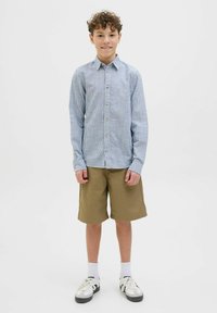 Camicia a maniche lunghe a righe blu e bianche abbinata a pantaloni cargo khaki, calze bianche e sneakers bianco e nere.