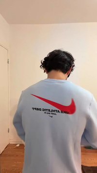 Light blue sweatshirt with a red Nike swoosh logo and black text saying "NIKE ATHLETIC DEPT. JUST DO IT." Relaxed fit, long sleeves.