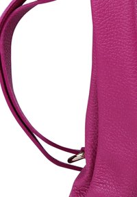 Close-up van een getextureerde magenta leer handtasband met zilveren gespdetails op een witte achtergrond.