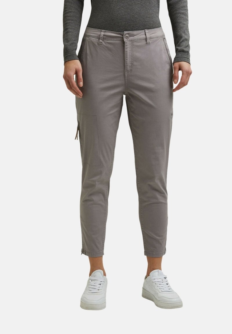 Pantalon cargo gris slim avec poche zippée latérale, associé à des baskets blanches et un haut à manches longues gris foncé, raccourci au-dessus des chevilles.