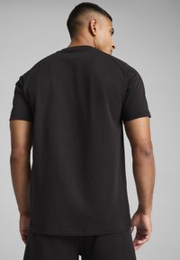 Svart kortärmad t-shirt i bomull. Har en rund halsringning och en slät textur. Baksidan visar en enkel design utan grafik.