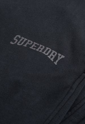 Donkergrijs stof met een gladde textuur, voorzien van het woord "SUPERDRY" in contrasterende lichtgrijze letters over het oppervlak.