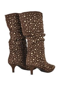 Botas de ante marrón con tachuelas doradas, diseño holgado, punta afilada y un tacón bajo. Cuentan con una cremallera lateral para facilitar su uso.