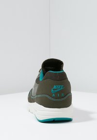 Nike Air Sneaker in dunkelgrün mit türkisfarbenen Akzenten. Obermaterial aus Mesh und Synthetik, runde Zehenpartie, gepolsterter Schaft und auffälliges Logo auf der Ferse.