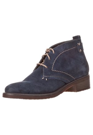 Bottine en daim bleu marine avec lacets beiges, surpiqûres contrastantes et un petit talon en bois empilé.